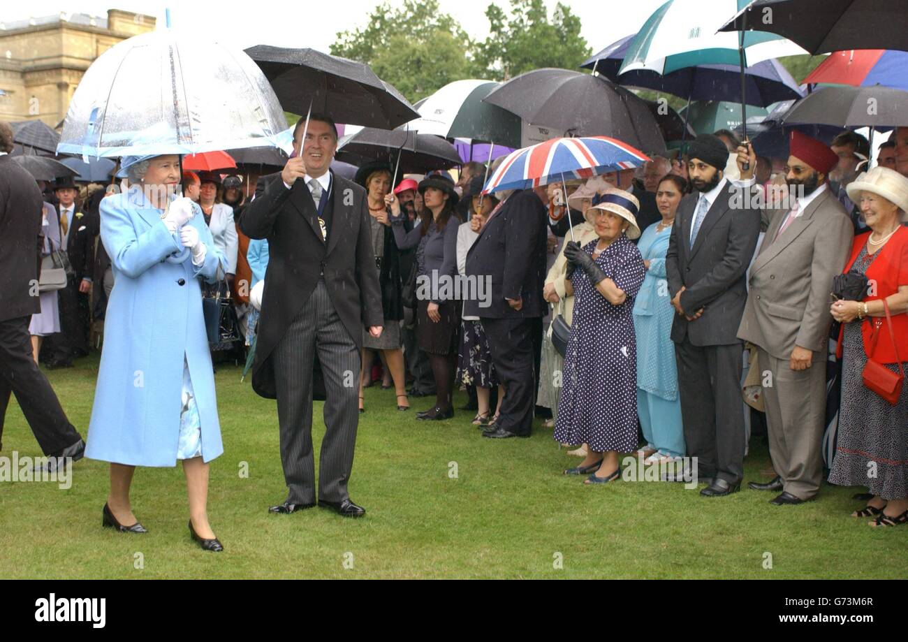 Königin Elizabeth II. Wird bei einer Gartenparty für die Royal Society of Arts in den Gärten des Buckingham Palace, London, von starkem Regen unerschrockt. Schwere Stürme haben Großbritannien in den letzten zwei Tagen heimgesucht, wobei Tausende von Menschen ihre Stromversorgung verloren haben. Stockfoto