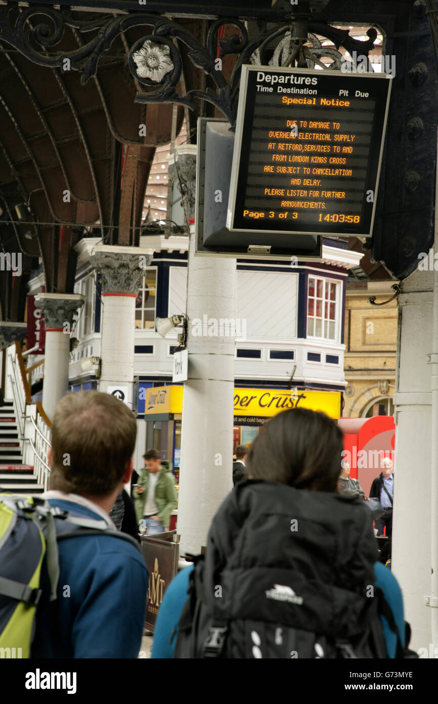 Passagiere am Bahnhof York, UK, Blick auf die Ankündigung der Verspätungen und Annullierungen auf Züge nach London Kings Cross. Stockfoto