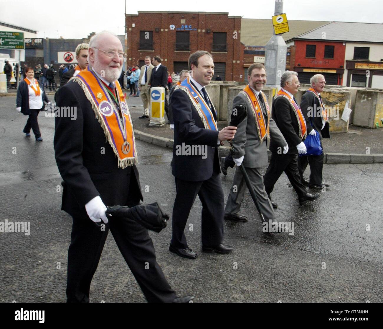 Nigel Dodds MP (zweite links), Spaziergänge vorbei an Ardoyne Geschäften mit anderen Orangemen und Bands in Nord-Belfast. Die Polizei hielt nationalistische Demonstranten und Orangemen auseinander, als sich die Zubringerparade von Orange Ballysillan in das Stadtzentrum begab, um an der Hauptparade in Belfast teilzunehmen. Die Feeder-Parade hat heute Abend Beschränkungen für ihre Rückreise, wobei die paraden-kommission urteilte, dass nur Orangemen am Ardoyne-Gebiet vorbeigehen dürfen; allen Bands und Anhängern wurde die Erlaubnis verweigert, die Orangemen auf der Rückreise zu begleiten. Politiker und Polizei haben für die Atmosphäre, die appelliert Stockfoto