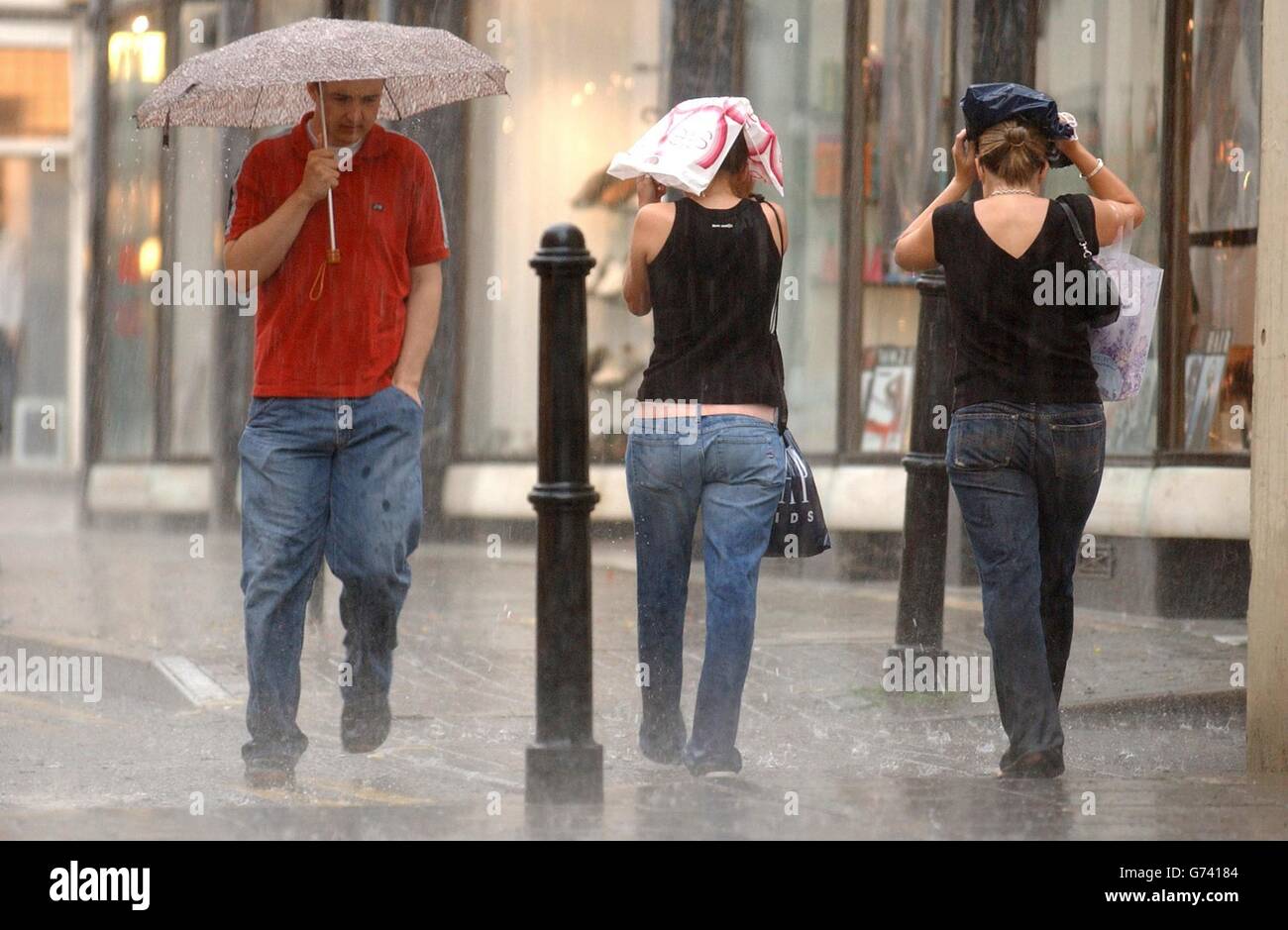 Shopper tun, was sie können, um während eines Regenguß im Zentrum von Cheltenham, Gloucestershire, trocken zu bleiben. Stockfoto