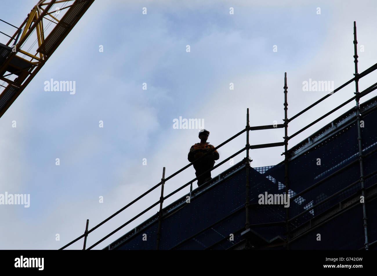 Ein Arbeiter einen remote Kran vom Dach eines Gebäudes in Betrieb Stockfoto