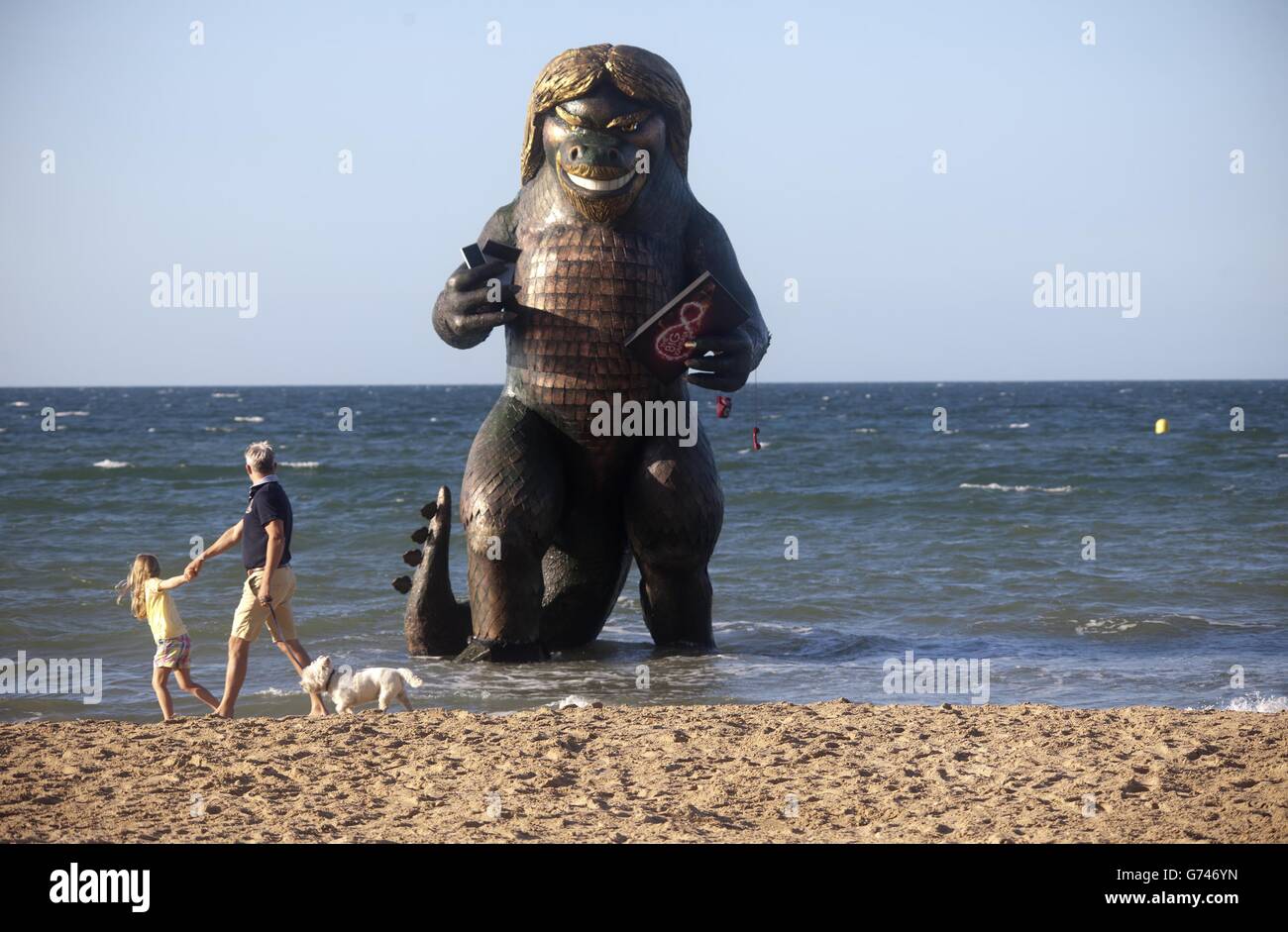 Eine 25 Meter hohe Seekreatur ähnlich Richard Branson taucht aus dem Meer auf Bournemouth Strand in Dorset mit einem TV, Laptop, Telefon und Handy, um die Einführung von Virgin Media Big Kahuna Quad-Play-Bundle zu feiern. Stockfoto