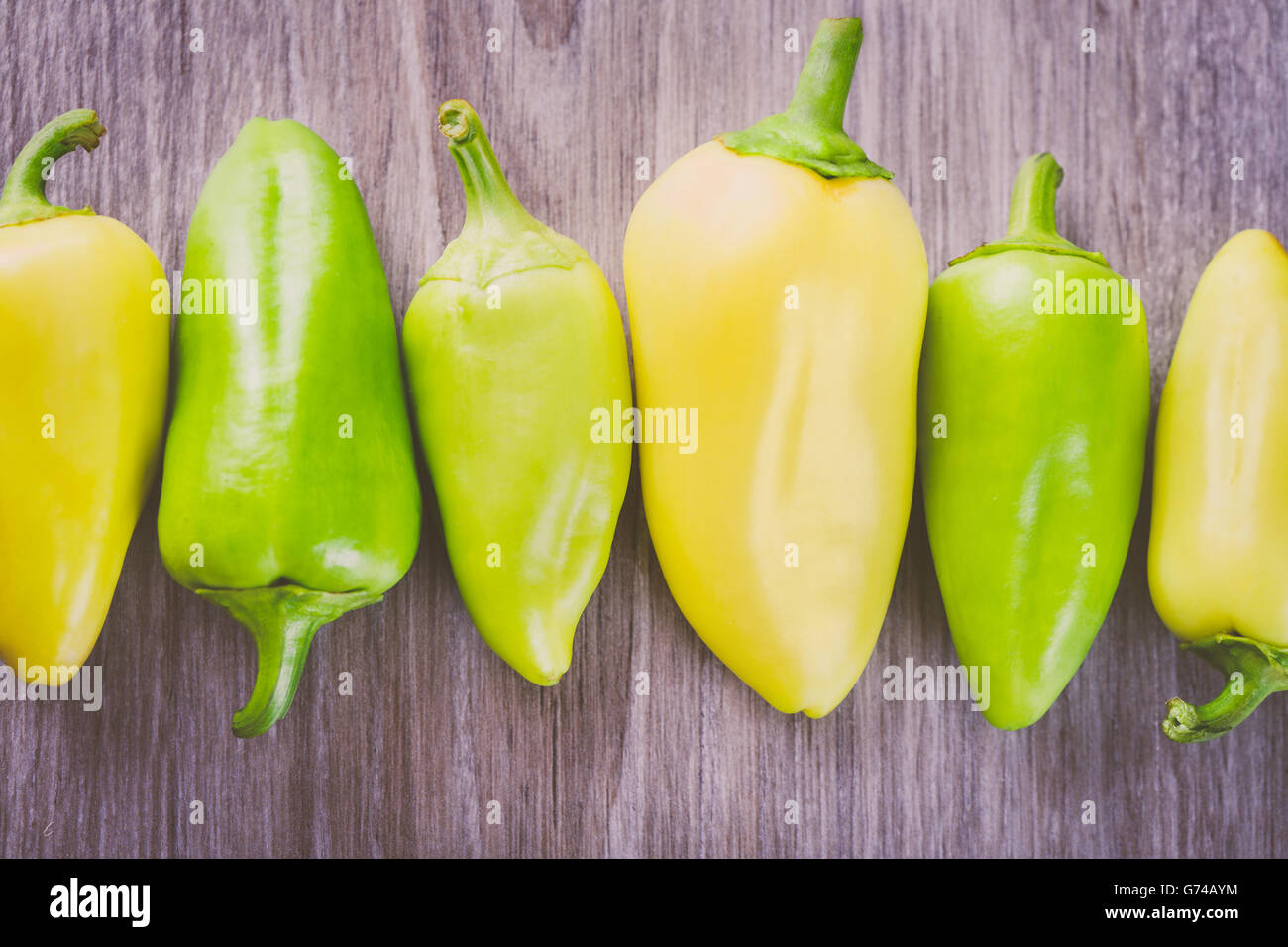 Einige grüne und gelbe Paprika in einer Reihe auf dem Tisch Stockfoto