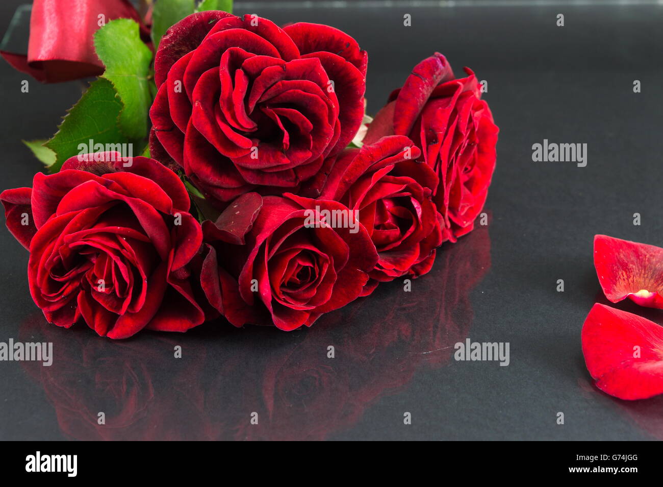 Rote Rosen-Bouquet mit Band am dunklen Spiegel Tisch Stockfoto