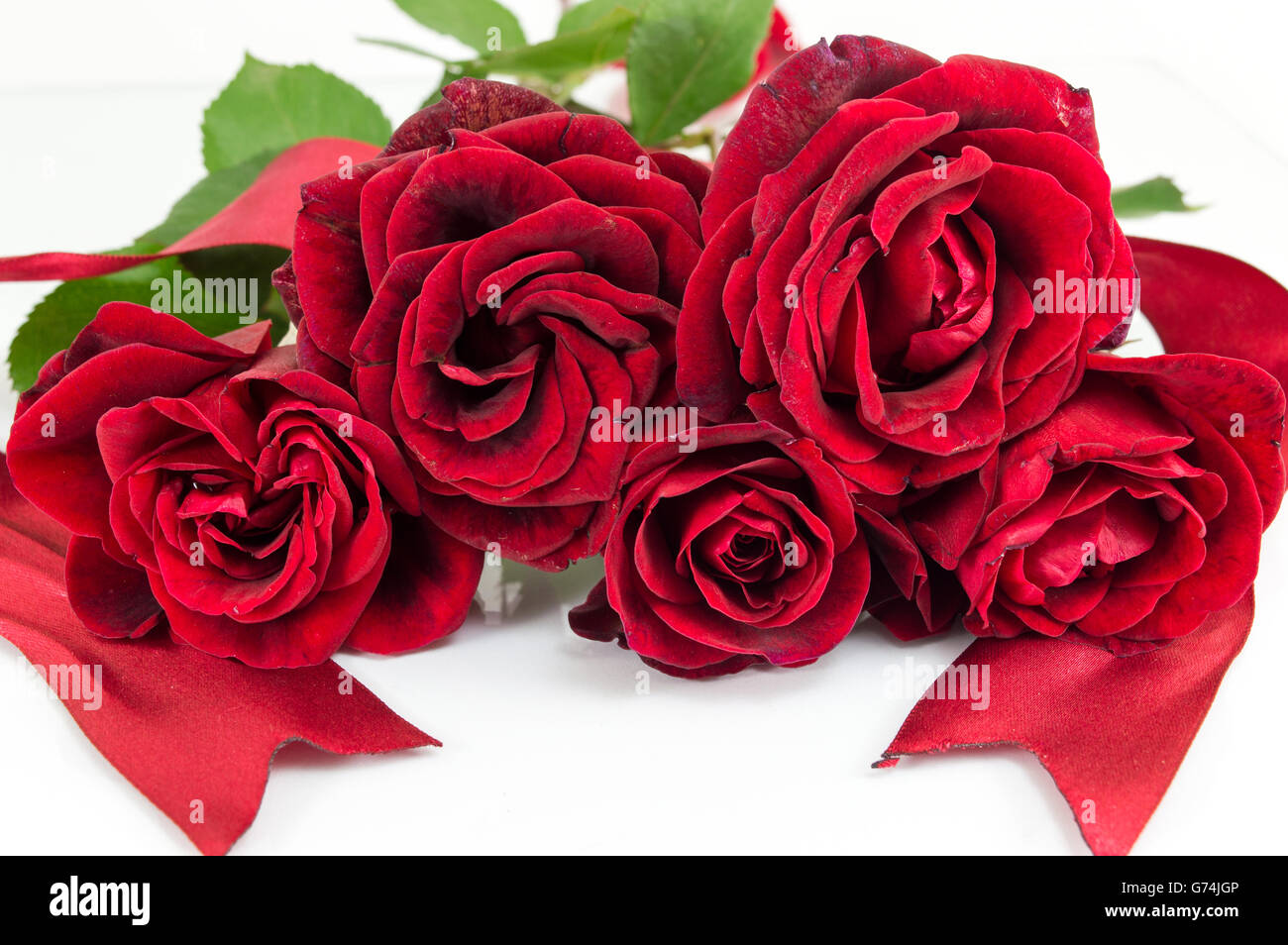 Rote Rosen mit einem Band am weißen Tisch Stockfoto