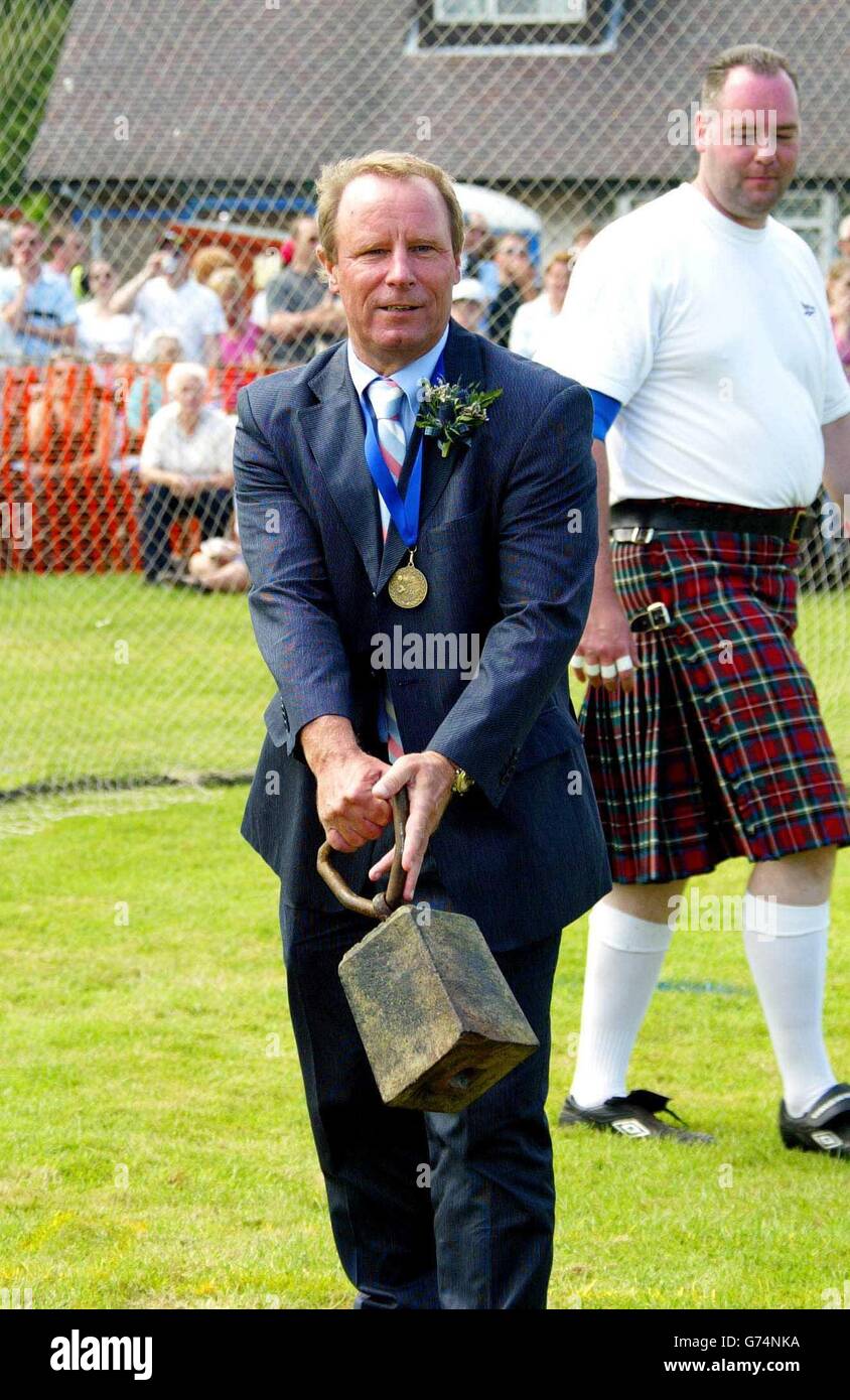 Der schottische Fußballmanager Berti Vogts hebt den Hammer bei Bridge of Allan Highland Games in der Nähe von Stirling, wo er in diesem Jahr Chefchieftan ist. Stockfoto
