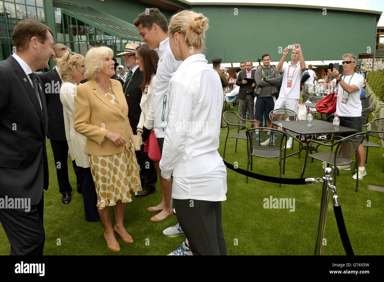 Am dritten Tag der Wimbledon Championships im All England Lawn Tennis and Croquet Club, Wimbledon, fotografieren Menschen, während die Herzogin von Cornwall mit dem Kanadier Milos Raonic spricht. Stockfoto