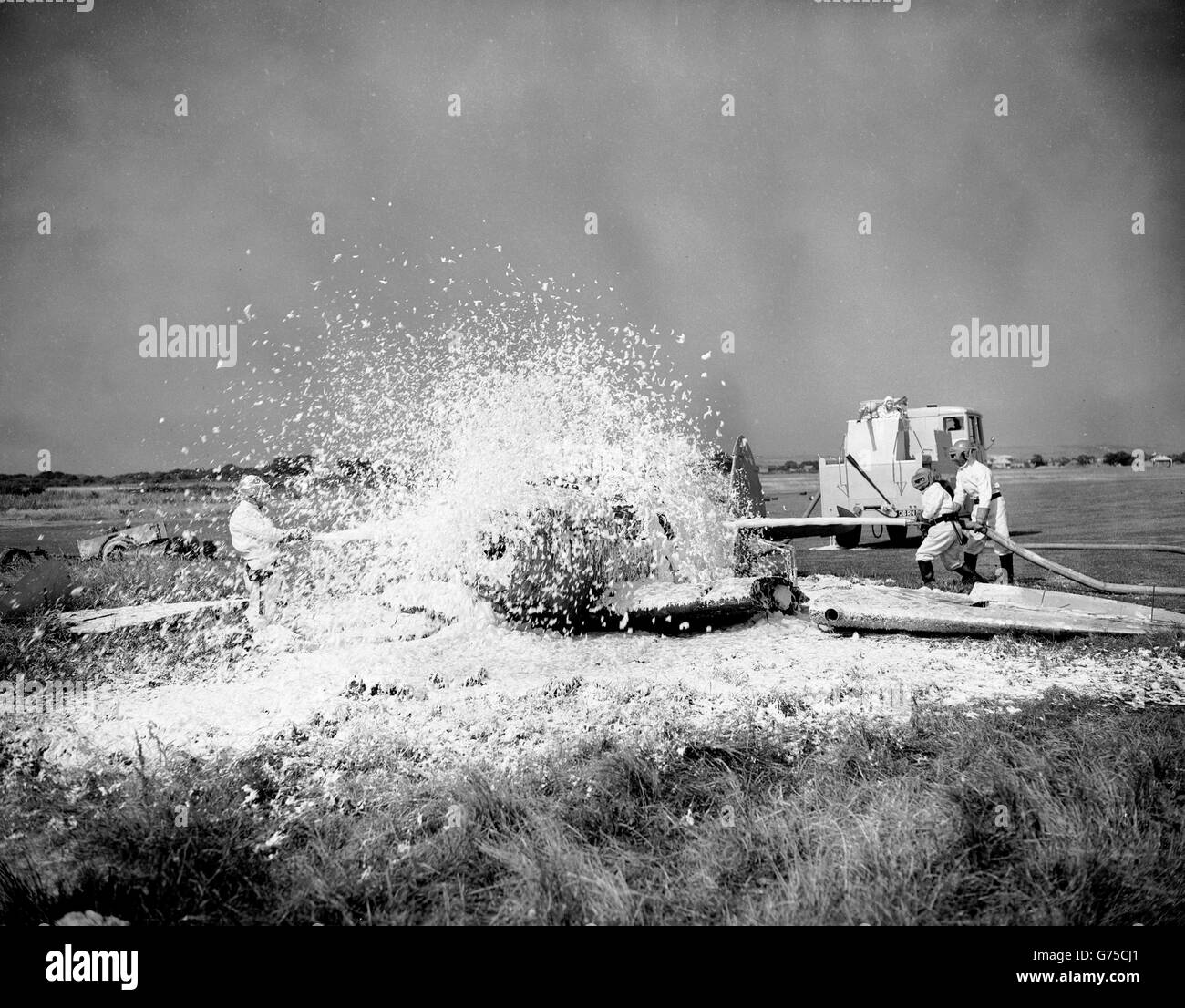 'Snow' fliegt als Männer von der Schule für Flugzeughandhabung, Gosport, Hampshire (bekannt für die Royal Navy als HMS Siskin), demonstrieren "Nubian", der Feuertender im Hintergrund gesehen, die neueste Art von Ausrüstung im Dienst, an der Royal Naval Air Service Station, Lee auf Solent. Ein Flugzeugbrand wird von (l-r) Naval Airman L. Fox aus Acton, London, A. E. Mulry, aus Rowland's Castle, Hampshire, und K. E. Reeves aus Exton, Hampshire, niedergeworfen. Der Betreiber auf dem Tender ist Naval Airman C. Sword, von Southend on Sea. Stockfoto