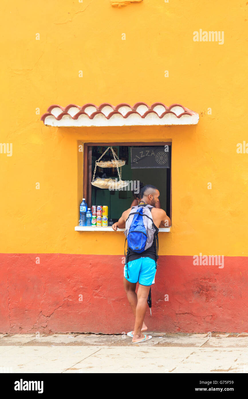 Junge Afro-Karibischen Mann Kauf Erfrischungen aus einem Geschäft oder Bar Fenster und Chat in Trinidad, Kuba Stockfoto