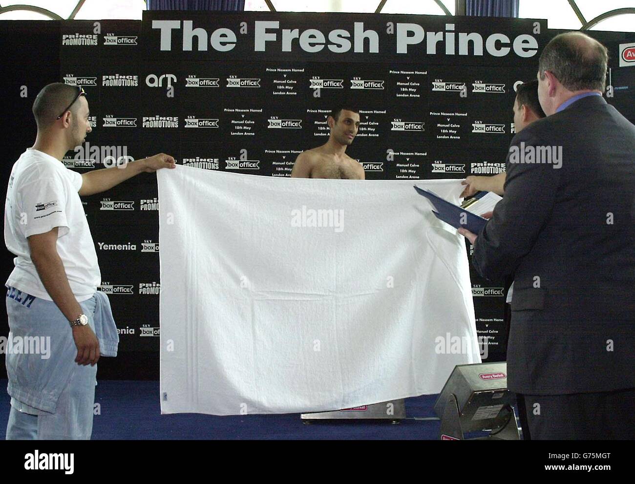 Prince Naseem Hamed muss mit einem Handtuch bedeckt werden, das Nabel (links) und Mourad von seinem Bruder hochhalten, während er seine Shorts auszieht, um das Gewicht in der Londoner Arena zu machen. Hamed tritt am Samstag in einem federleichten Titelkampf der IBO gegen Manuel Calvo an. Stockfoto