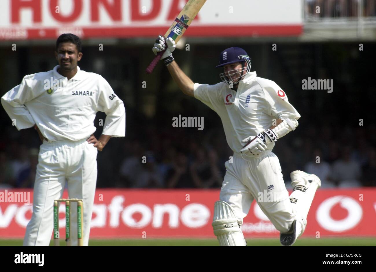 Der englische Opener Michael Vaughan feiert sein Jahrhundert, während Bowler Anil Kumble am vierten Tag des 1. Tests gegen Indien bei Lord's anschaut. Stockfoto