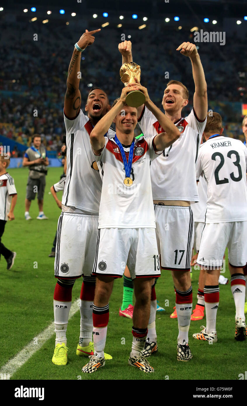 Deutschlands Thomas Muller feiert mit der FIFA auf dem Platz WM 2014 Trophy neben Teamkollegen per Mertesacker (rechts) und Jerome Boateng (links) Stockfoto