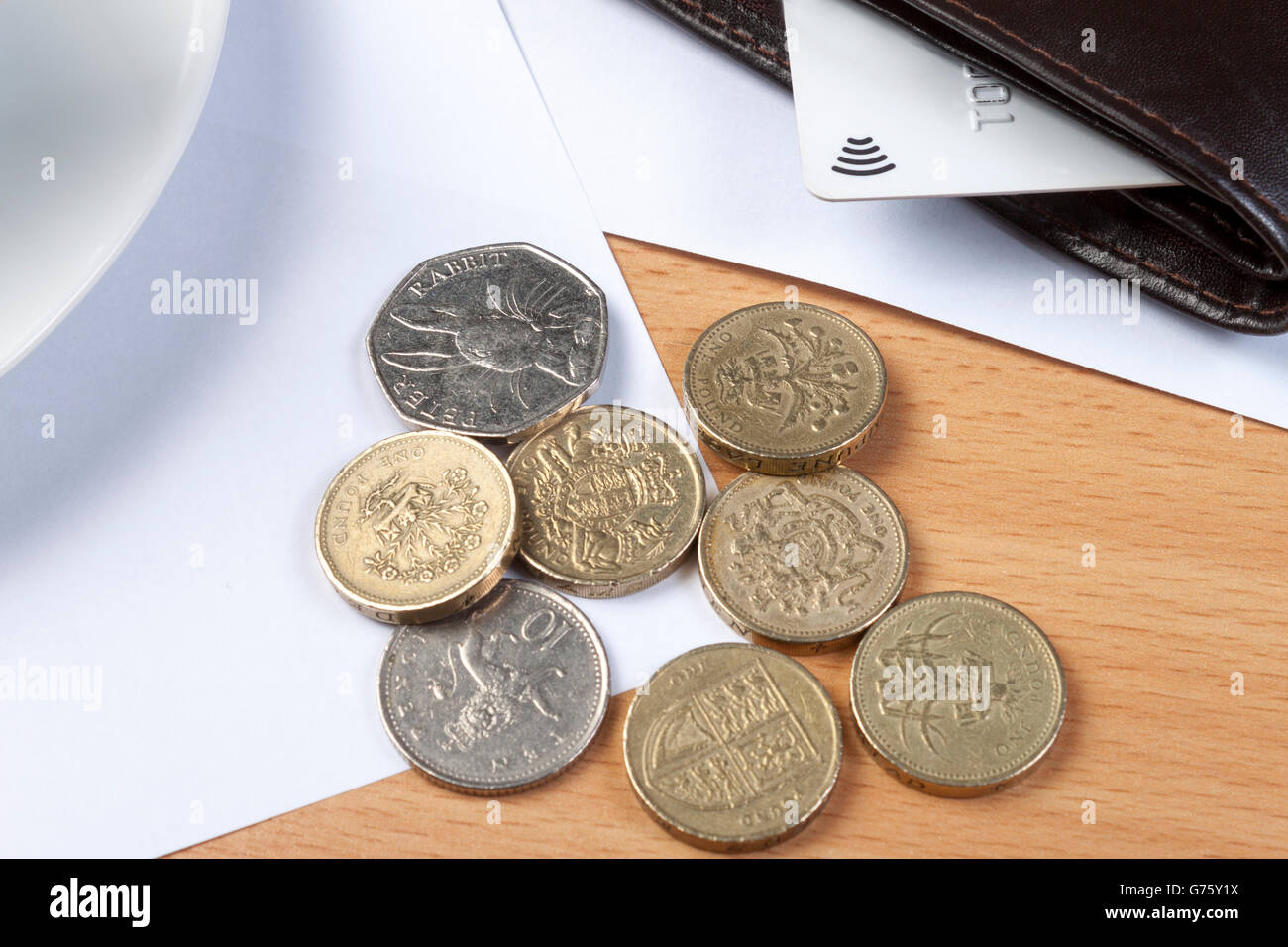 Schuss von einigen Münzen neben eine Brieftasche mit einer Kreditkarte darin auf ein Buchhalter Schreibtisch Nahaufnahme Stockfoto