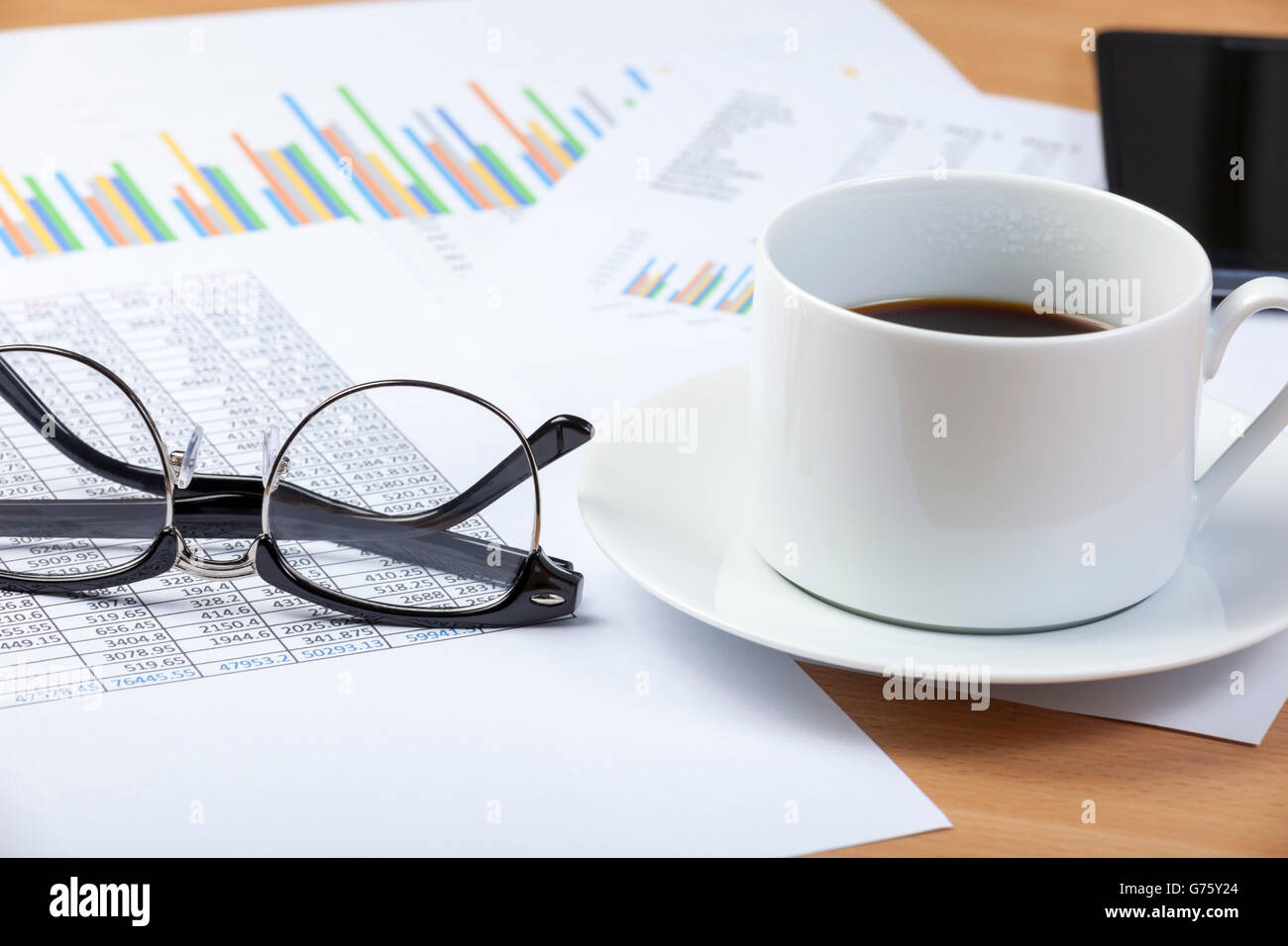 Tasse schwarzen Kaffee und ein paar Brillen Handauflegen eines Buchhalters Schreibtisch auf einer Tabellenkalkulation und einige Grafiken Stockfoto