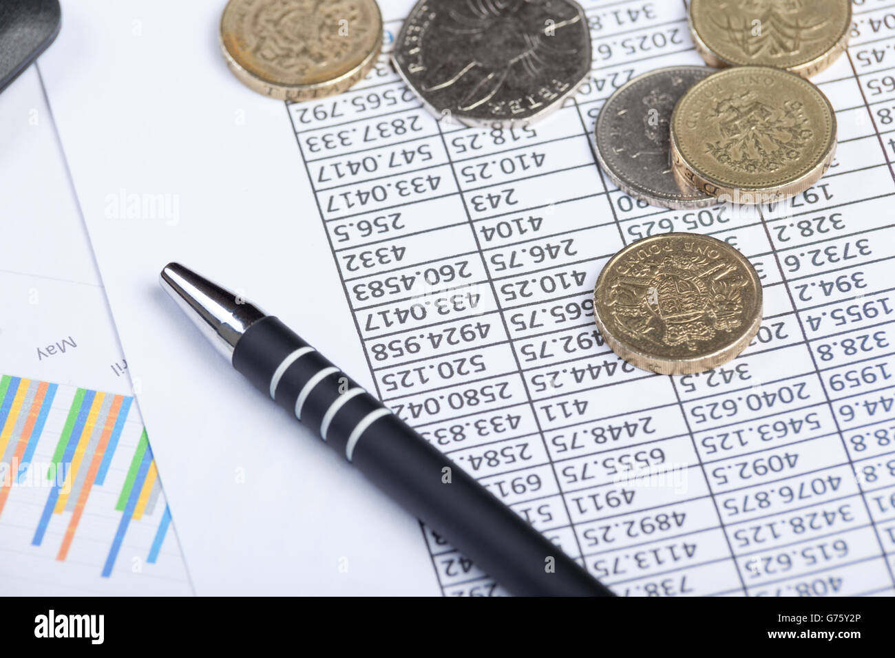 Buchhalter Desktop mit einem Stift und einige Münzen Verlegung auf eine Ausbreitung Blatt Amd ein Diagramm Stockfoto