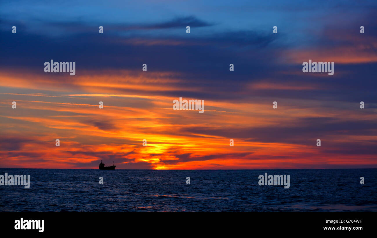 Schöne Landschaft, dramatische orange Sonnenuntergang über Meer, Schiff Silhouette über Himmelshintergrund, Schönheit der Natur Sommer Abend Stockfoto