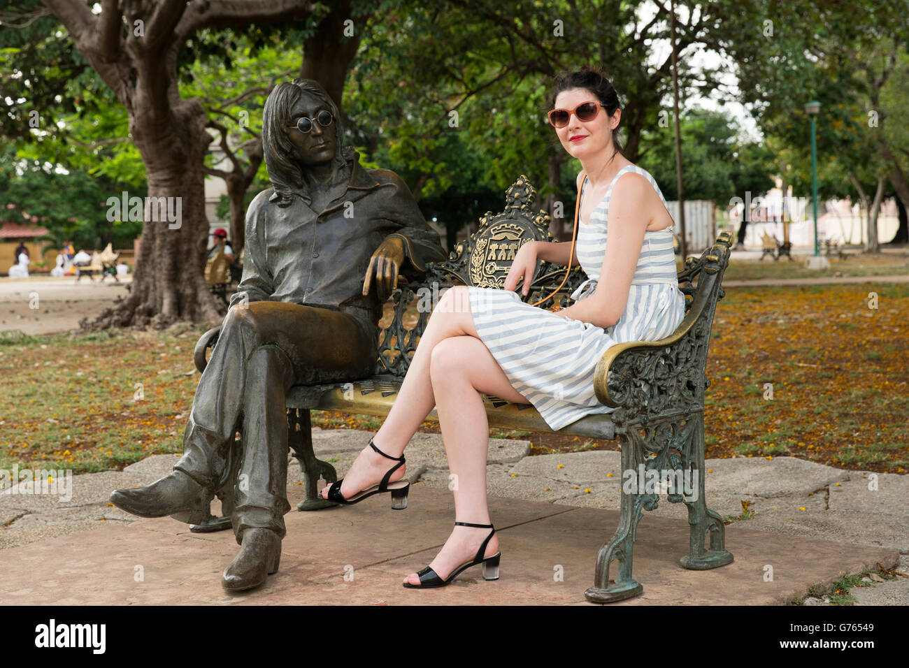 Eine Frau sitzt mit der Statue von John Lennon John Theodore Lennon Park in Havanna, Kuba Stockfoto