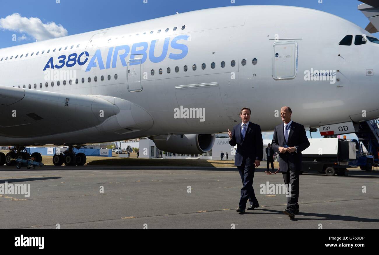Premierminister David Cameron (links) und Tom Enders, der Vorstandsvorsitzende der Airbus Group, gehen bei einem Besuch der Farnborough Airshow 2014 in Hampshire an einem Airbus A380 vorbei, um den neuen Airbus A350 zu inspizieren. Stockfoto