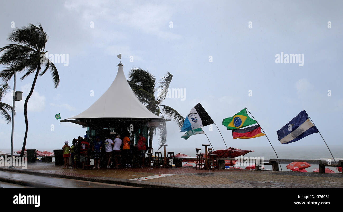 Fußball - FIFA Fußball-Weltmeisterschaft 2014 - Runde 16 - Costa Rica gegen Griechenland - Arena Pernambuco. Die Menschen versuchen, sich vor dem strömenden Regen an einem Strand in Recife zu schützen Stockfoto