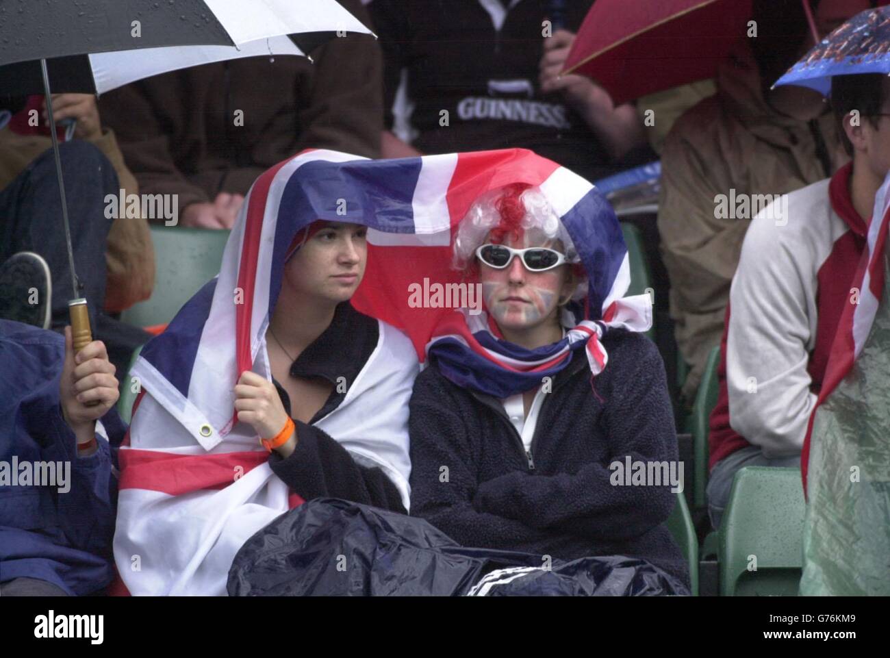 FÜR , KEINE KOMMERZIELLE VERWENDUNG. Tennisfans auf dem Court One in Wimbledon decken sich beim Spiel zwischen dem britischen Nummer-eins-Tennisstar Tim Henman und dem Schweizer Michel Kratochvil vor einem plötzlichen Regenschauer. *... in der vierten Runde auf Court One in Wimbledon. Stockfoto