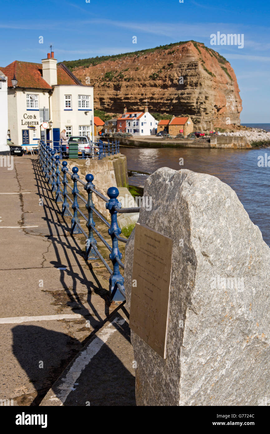 Großbritannien, England, Yorkshire, Staithes, High Street, direkt am Meer Flut Abwehrkräfte Gedenktafel neben Hafen Stockfoto