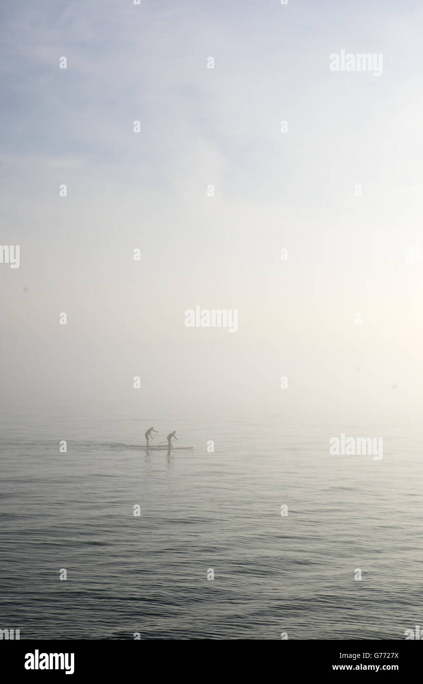 Zwei Paddleboarders machen ihren Weg durch den Nebel in Hove. Stockfoto