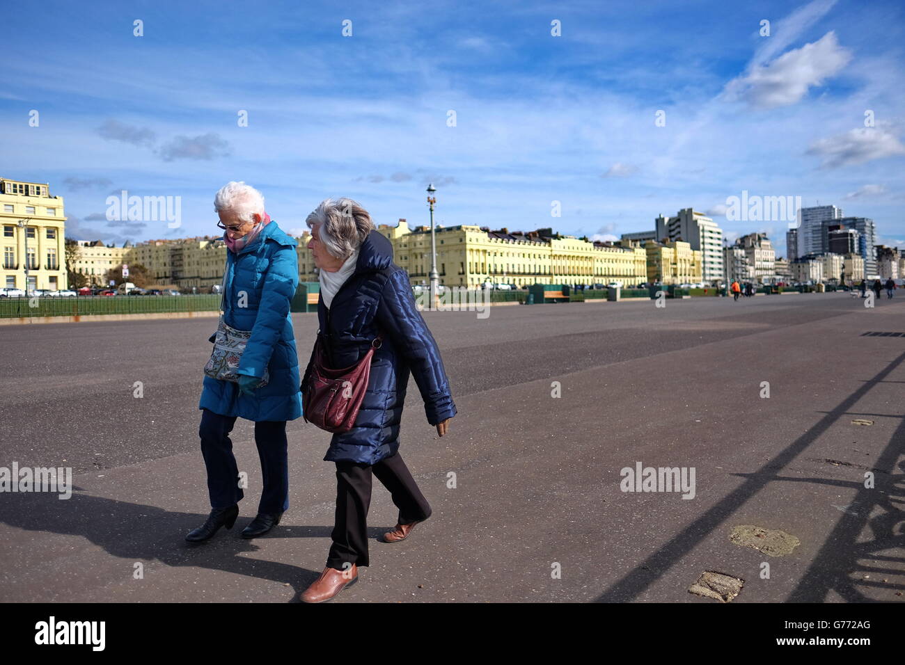 Zwei ältere Damen, die zu Fuß am Meer in Hove, East Sussex, Großbritannien Stockfoto