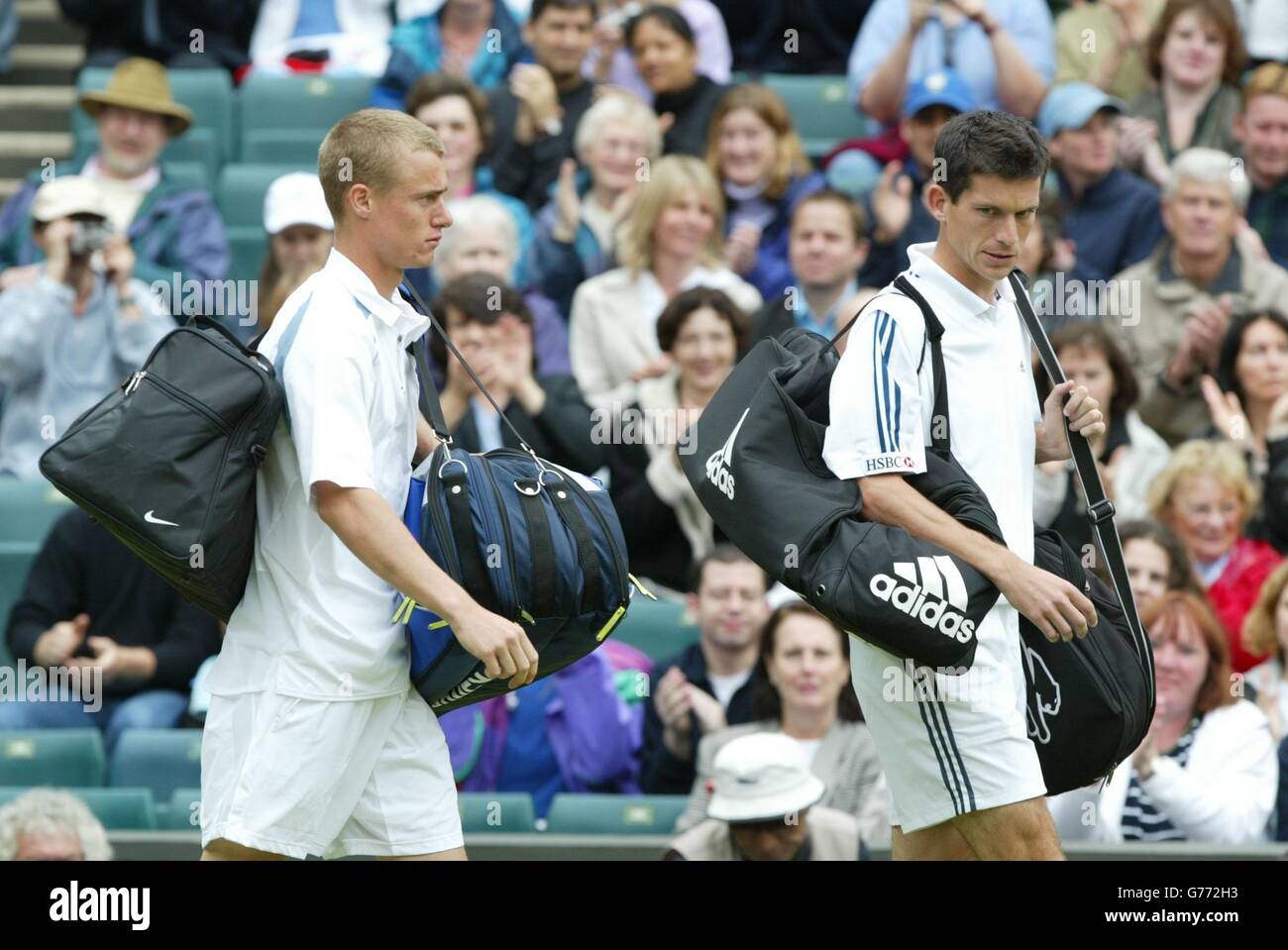 NUR ZUR REDAKTIONELLEN VERWENDUNG, KEINE KOMMERZIELLE NUTZUNG : der britische Tim Henman (rechts) trifft am Center Court in Wimbledon ein, gefolgt von dem Spitzengesät Lleyton Hewitt aus Australien für ihr Halbfinale. Regen zwang die Spieler nach ihrem fünfminütigen Warm-up, ohne einen einzigen Punkt zu spielen. PA Foto: Nick Potts. Stockfoto