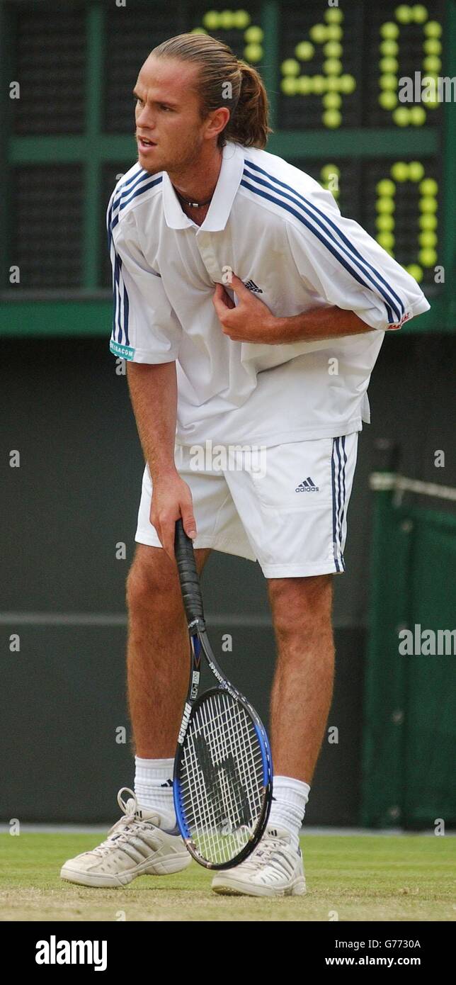 NUR FÜR REDAKTIONELLE ZWECKE, KEINE KOMMERZIELLE VERWENDUNG. Xavier Malisse aus Belgien hält sich während seines Halbfinalmatches gegen den Argentinier David Nalbandian vor Gericht 1 in Wimbledon die Brust. Malisse verließ das Gericht für zehn Minuten, um ärztliche Hilfe zu erhalten, nachdem er den ersten Satz der Krawatte verloren hatte. Stockfoto