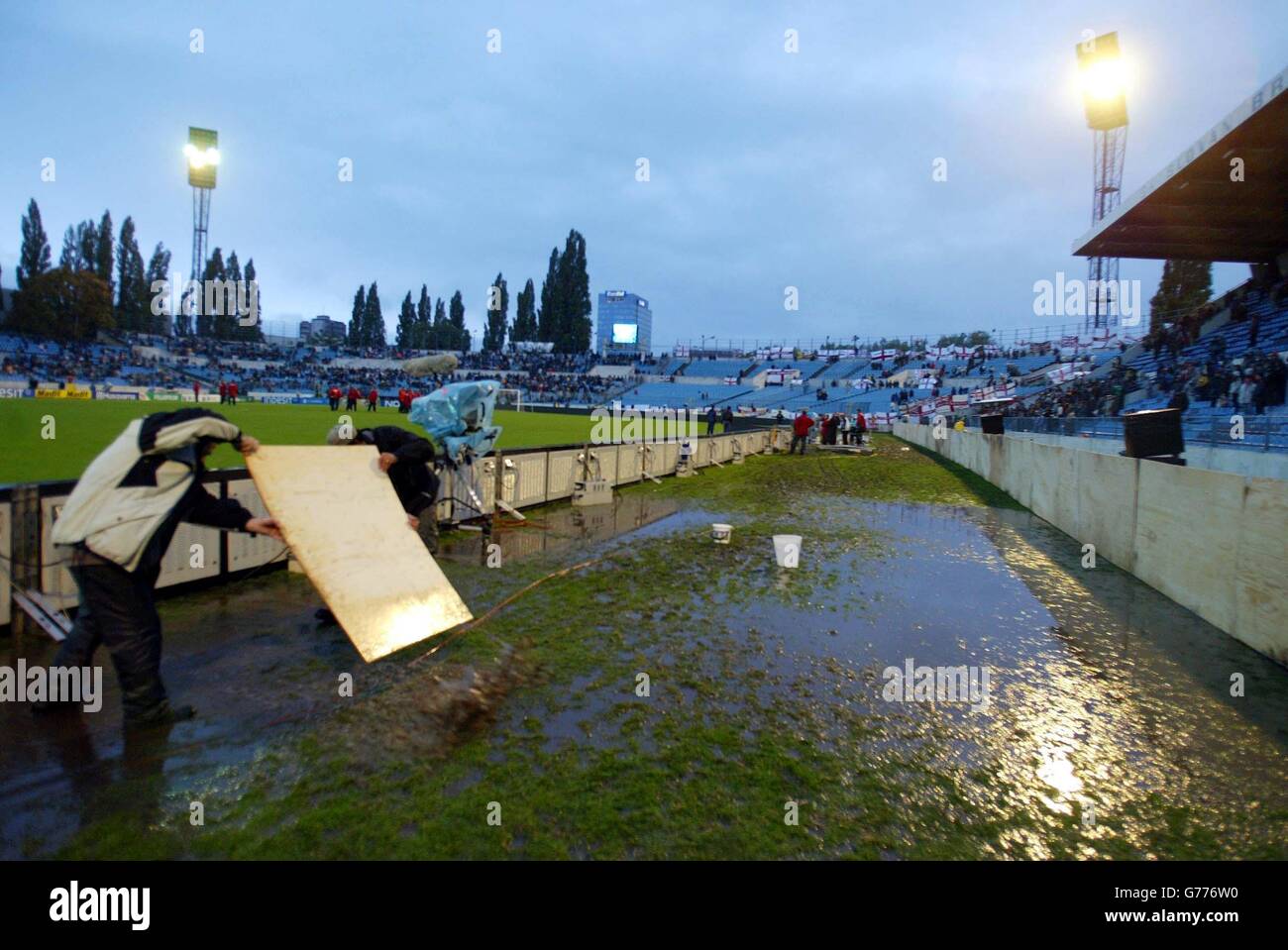 Es werden verschiedene Methoden verwendet, um das Spielfeld im Tehele Pole Stadium in Bratislava in der Slowakei vor dem englischen EM 2004 Qualifier gegen die Slowakei zu entleeren. Das Spiel wird Schieß los. trotz schwerer Regengüsse, die zunächst das Spiel in Zweifel zu stellen. Stockfoto