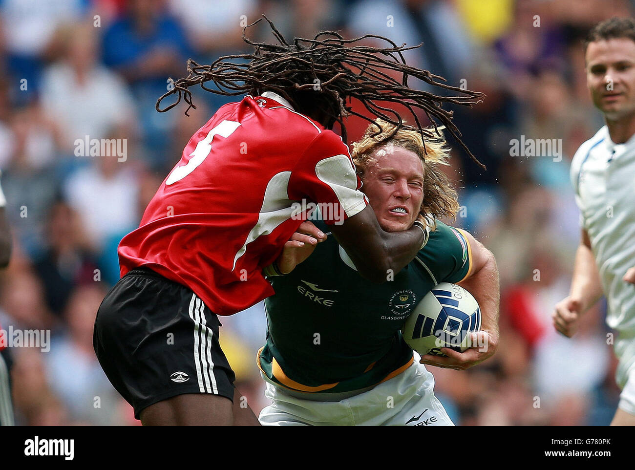 Der Südafrikaner Werner Kok wird von Trinidad und Agboola Silverthorn von Tobago während des Rugby-7-Turniers im Ibrox-Stadion während der Commonwealth Games 2014 in Glasgow angegangen. Stockfoto