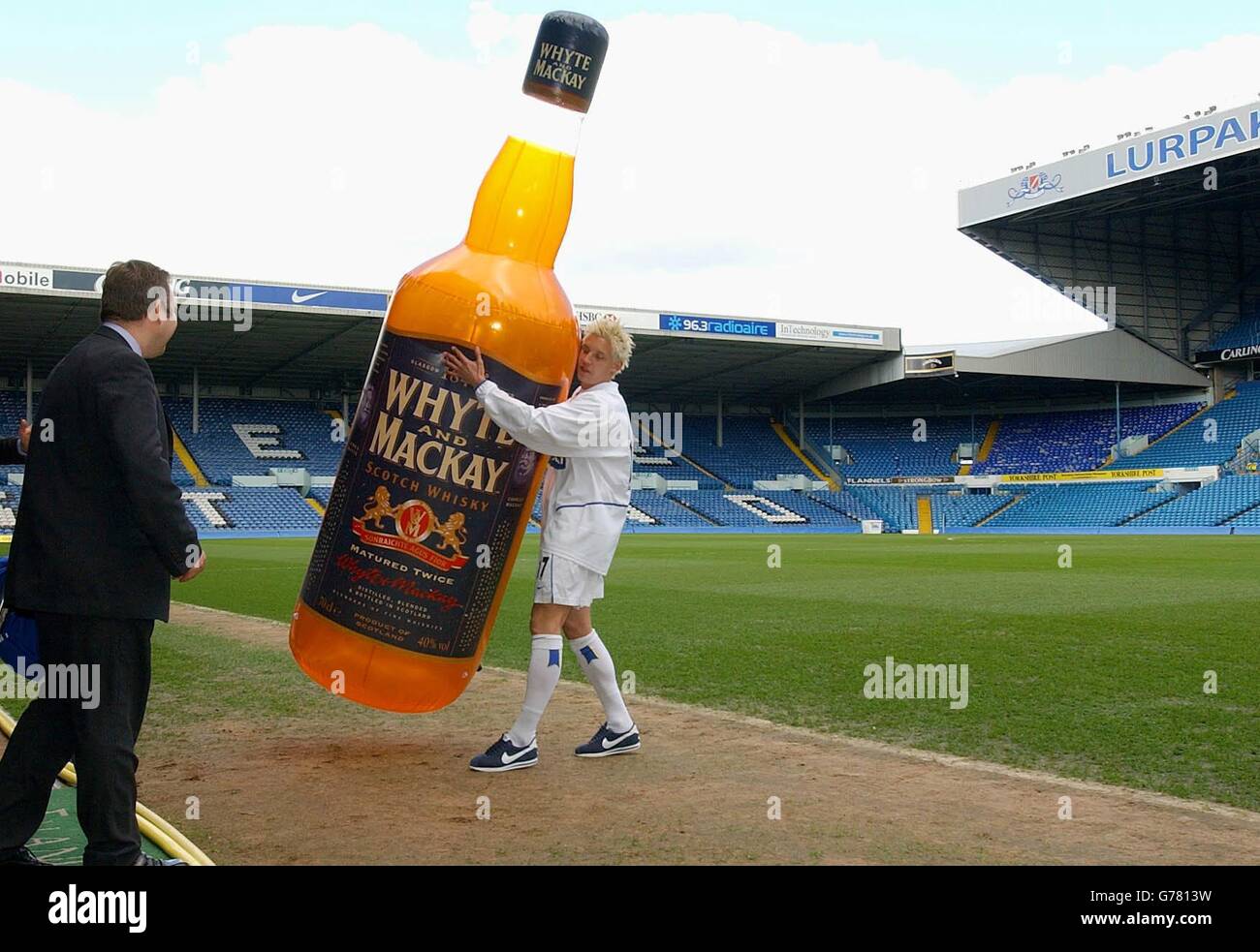 Der Stürmer von Leeds United, Alan Smith, trägt eine große Replik-Flasche der neuen Multi-Millionen-Pfund-Sponsoren des Clubs, Whyte und Mackay Whisky, von ihrem Elland Road Pitch, nachdem der neue Sponsorenvertrag für Leeds bekannt gegeben wurde. Stockfoto