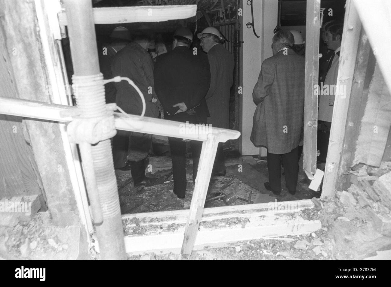 Ein Blick durch einen zerbrochenen Fensterrahmen in das von der Bombe gestrahlte öffentliche Haus von Horse and Groom wird vom Innenminister Roy Jenkins (Mitte) besucht. Stockfoto