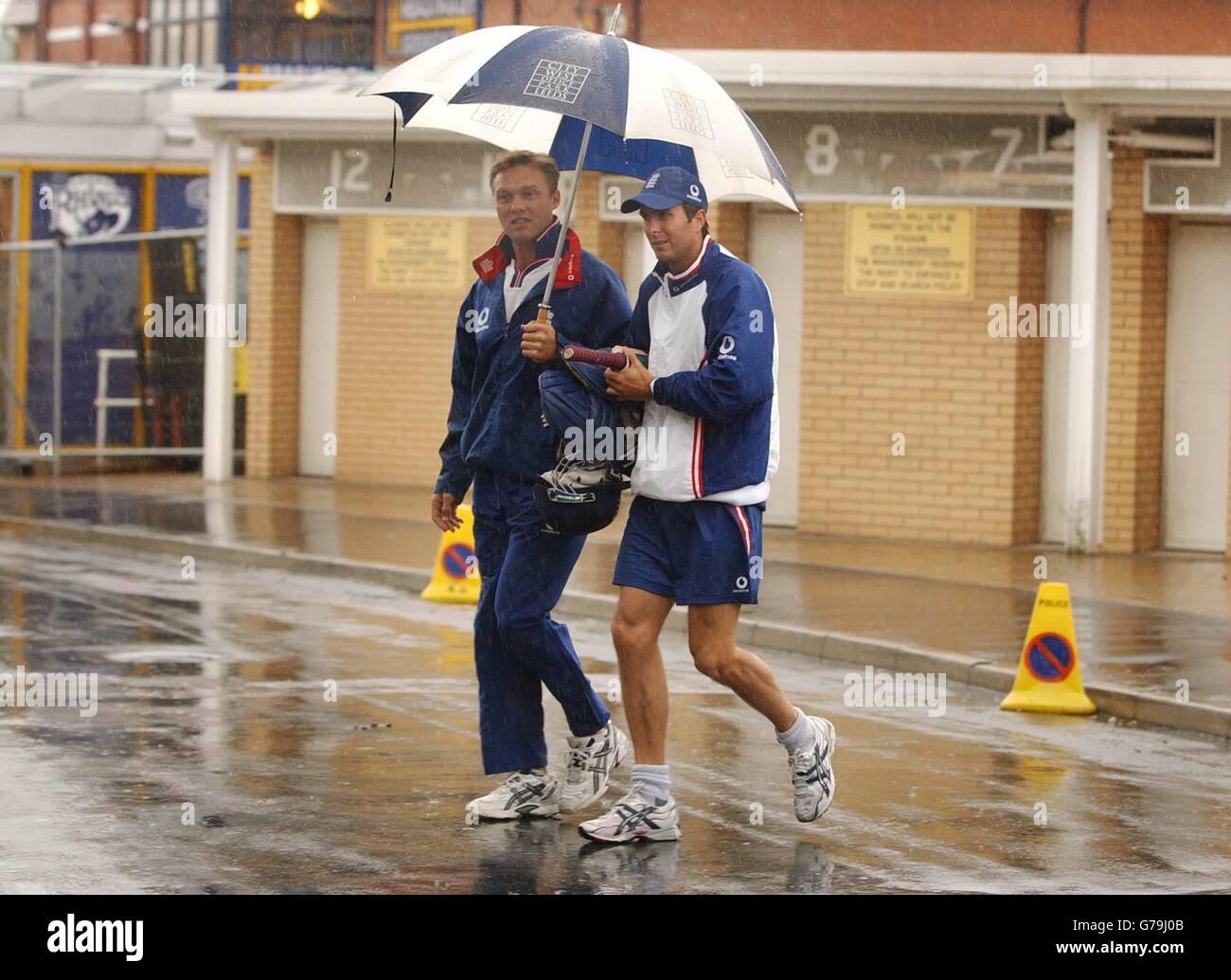 Der englische Physio Nigel Stockhill (links) und Kapitän Michael Vaughan machen sich wegen des Regens vom Headingley in Leeds auf den Weg zum Indoor-Netztraining, vor dem englischen NatWest Series-Spiel gegen Simbabwe am 1. Juli. Stockfoto