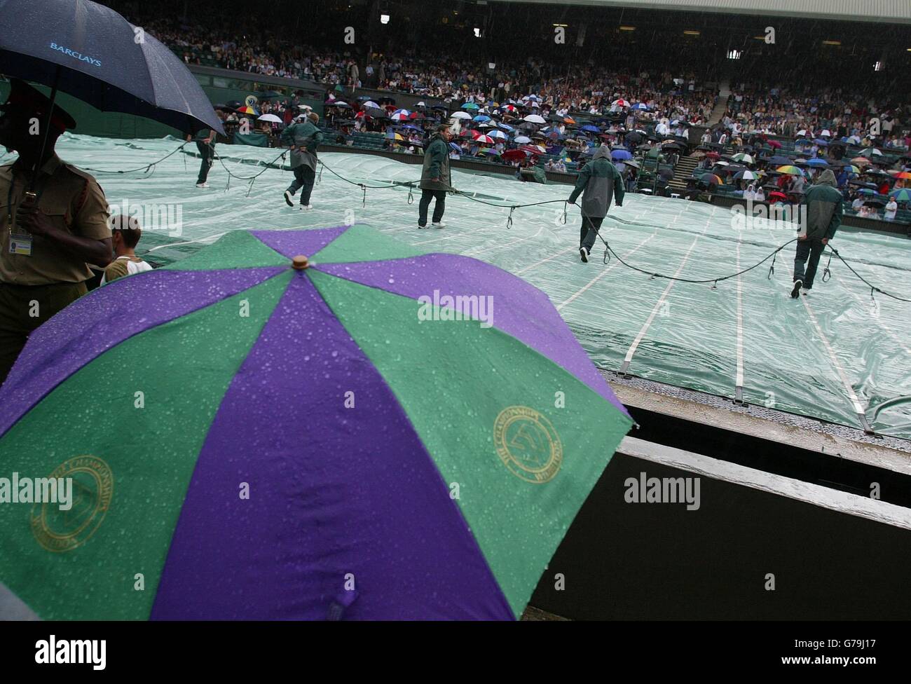 , KEINE HANDY-NUTZUNG EINE heftige Regendusche zwingt zu einem Einbruch in die vierte Runde Spiele bei den All England Lawn Tennis Championships in Wimbledon. Stockfoto