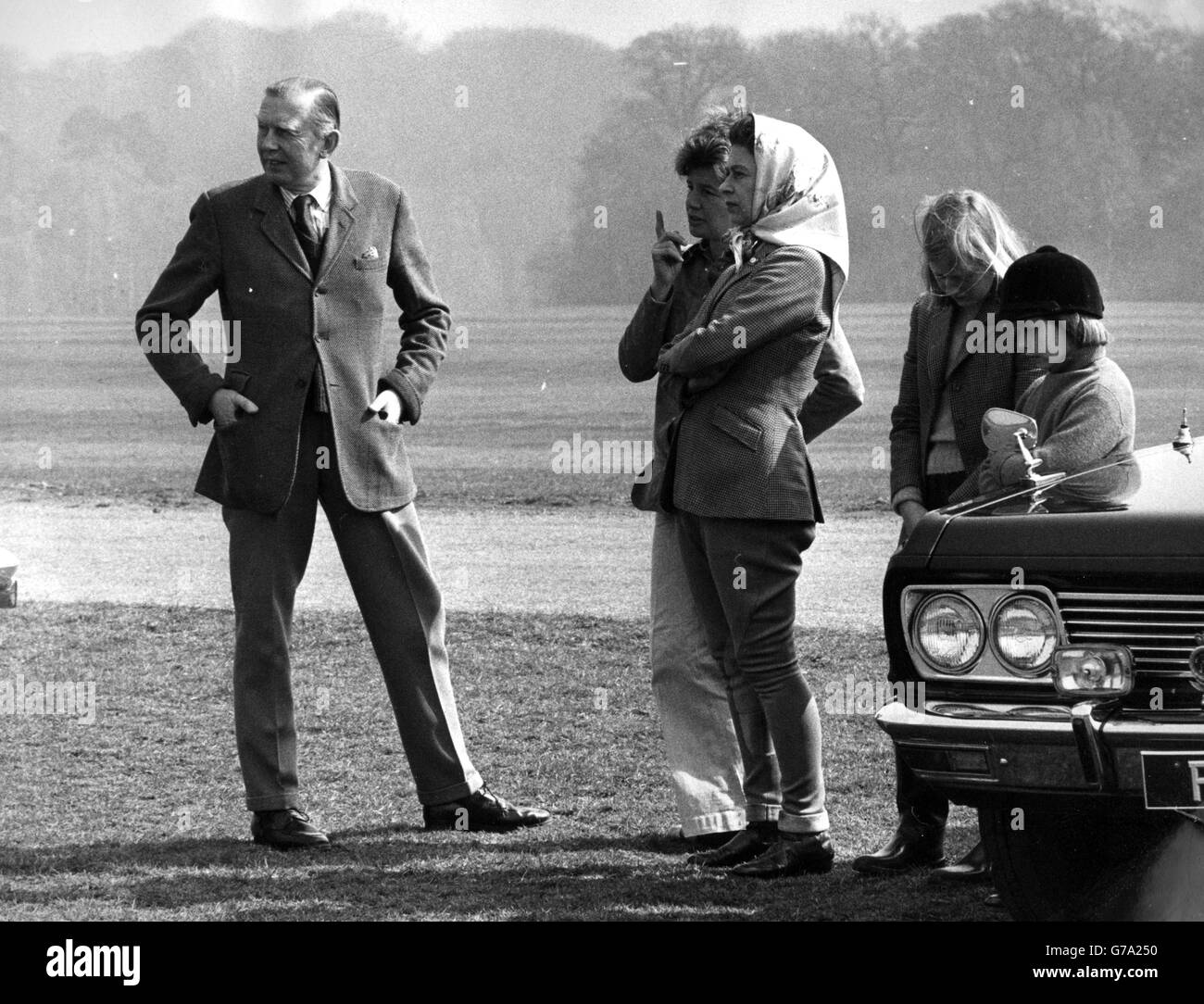 Die Königin, in Jodhpins und einem Kopftuch, spricht mit Trainer Alison Oliver bei den zweitägigen Windsor Horse Trials. Hinter ihnen stehen Prinzessin Margarets Tochter Lady Sarah Armstrong-Jones und die 11-jährige belgische Prinzessin Astrid, Tochter von Prinz Albert und Nichte von König Baudoin. *Scannen aus dem Druck. Hochauflösende Version auf Anfrage erhältlich* Stockfoto