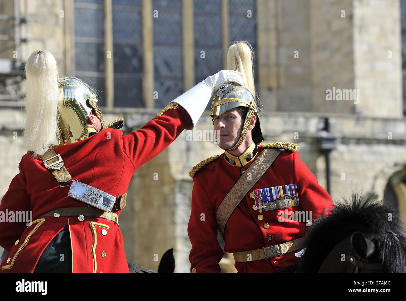Eine helfende Hand für eine eigensinnige Wolke auf dem zeremoniellen Helm einer königlichen Dragoonensgarde, als sie sich auf den Weg vom York Minster vorbereiteten, wo sie durch die Stadt zogen und dann im Rahmen der Gedenkfeiern des Ersten Weltkriegs einen Gottesdienst im Münster abhielten. Stockfoto