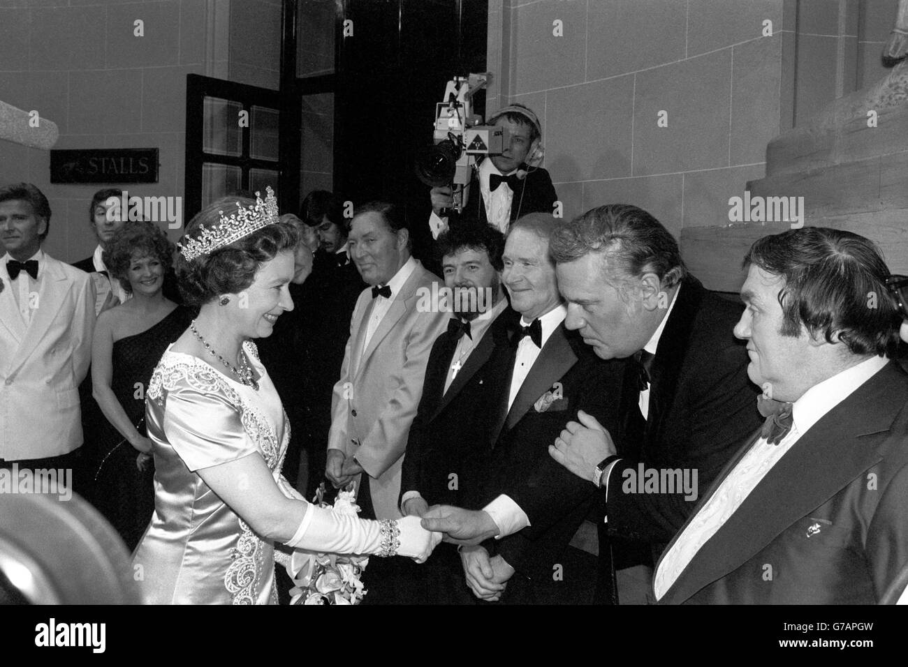 Die Queen schüttelt sich die Hände mit dem Überraschungsgast der Royal Variety Performance gestern Abend, dem ehemaligen ITN-Nachrichtensprecher Reginald Bosanquet, der in dem traditionell verstorbenen Dame Gracie Fields-Spot auftrat, der das Finale einführte. Andere im Line-up nach der Show im Theatre Royal in Drury Lane sind der Komiker Les Dawson (r) und (von l-r) Bill Haley, der Flötist James Galway und Red Buttons. Stockfoto Die Queen schüttelt sich die Hände mit dem Überraschungsgast der Royal Variety Performance gestern Abend, dem ehemaligen ITN-Nachrichtensprecher Reginald Bosanquet, der in dem traditionell verstorbenen Dame Gracie Fields-Spot auftrat, der das Finale einführte. Andere im Line-up nach der Show im Theatre Royal in Drury Lane sind der Komiker Les Dawson (r) und (von l-r) Bill Haley, der Flötist James Galway und Red Buttons. Stockfoto