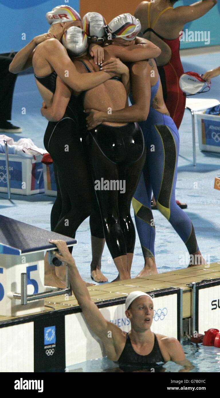 Die deutsche Freistil 4-Staffelmannschaft der Frauen feiert ihre Bronzemedaille, als die britische Karen Pickering (unten) im Pool steht, nachdem die britische Mannschaft im olympischen Aquatic Center in Athen, Griechenland, den fünften Platz belegte. Stockfoto