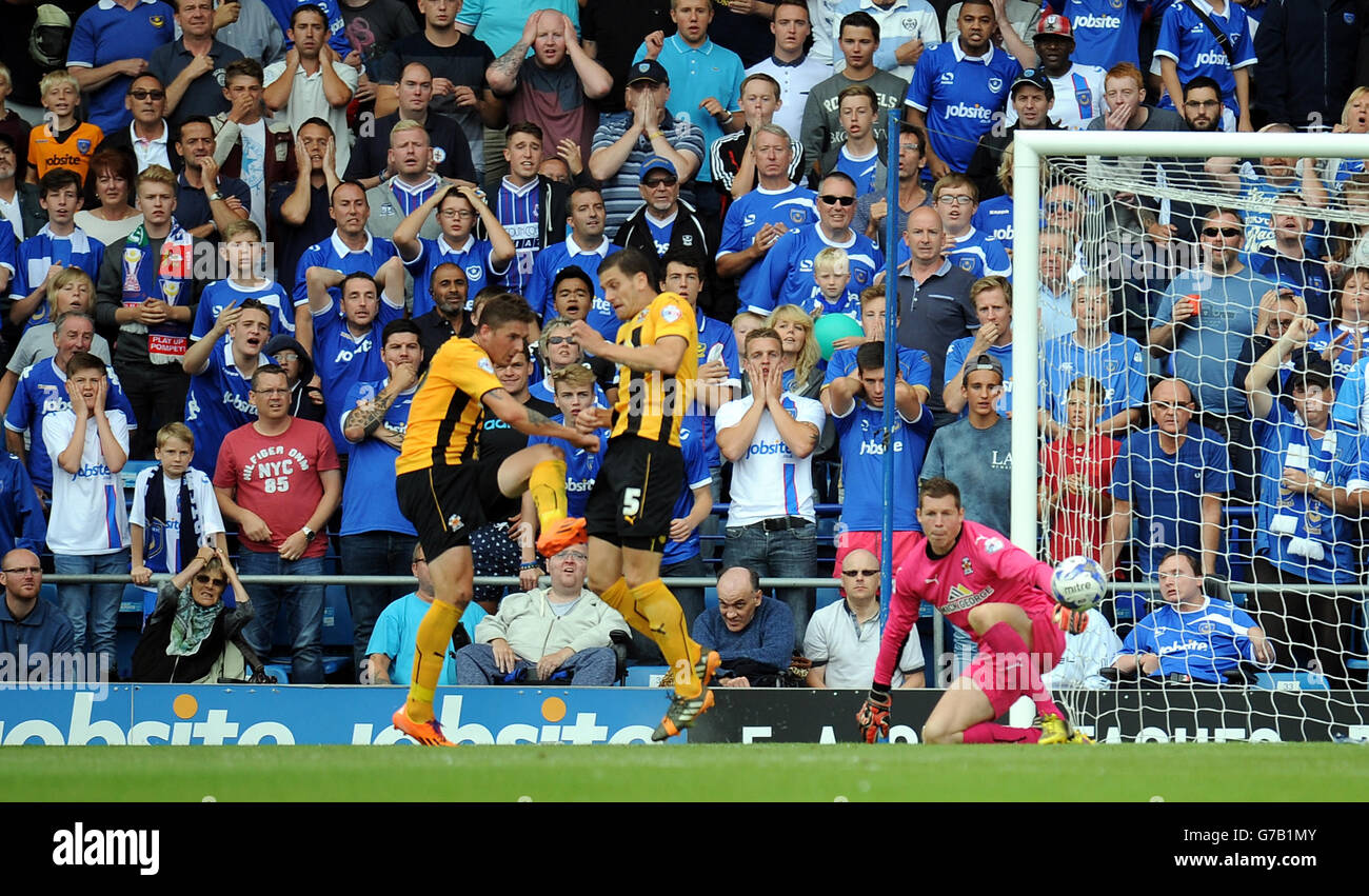 Liam Hughes von Cambridge United (links) schneidet den Ball an seinem eigenen Torwart vorbei, um 2-0 Punkte nach Portsmouth zu holen. Stockfoto