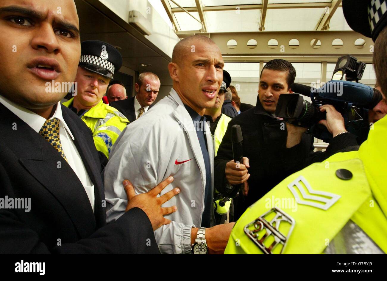 Barcelona und der ehemalige keltische Stürmer Henrik Larsson (Mitte) kommen am Glasgow International Airport an, als er von Betreuern und Strathclyde Polizisten begleitet wird. Barcelona spielen Celtic in der ersten Runde der Champions League im Parkhead Stadium, morgen. Stockfoto