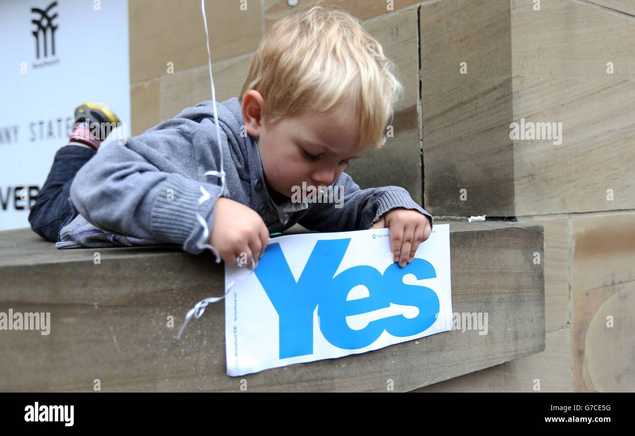 Ein Kind spielt mit einem Schild während einer Yes-Wahlkampfveranstaltung vor der Glasgow Concert Hall vor dem schottischen Unabhängigkeitsreferendum, das morgen stattfindet. Stockfoto