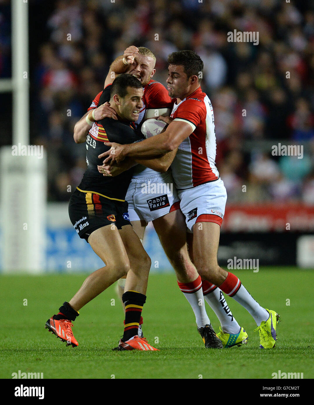 Michael Oldfield von Catalan Dragons wird von Luke Thompson von St. Helens und Mark Flanagan (rechts) während des ersten Play-Off-Spiels der Utility Super League im Langtree Park, St. Helens, angegangen. Stockfoto