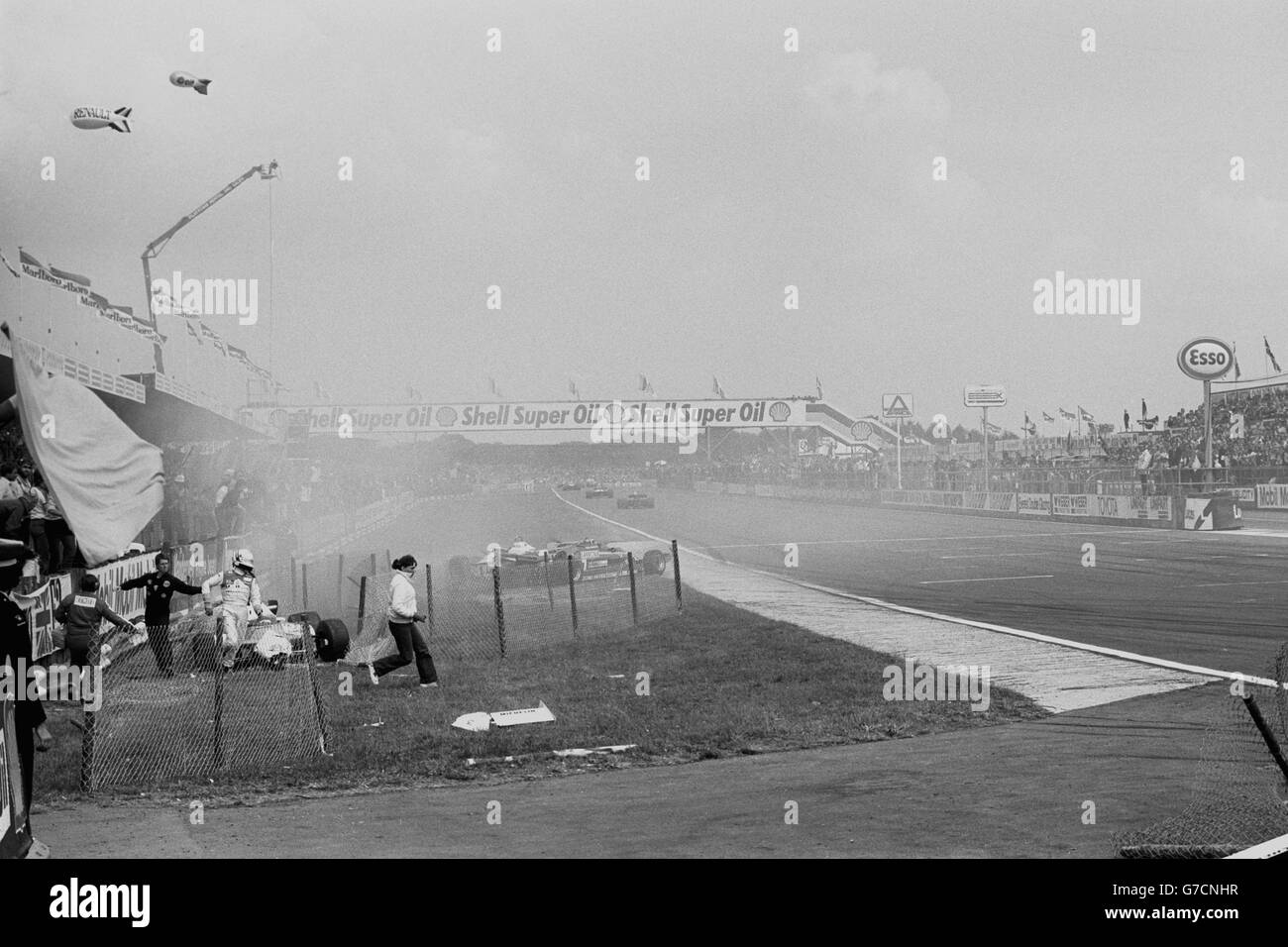 Der italienische Rennfahrer Andrea de Cesaris läuft von seinem Marlboro McLaren ab, nachdem das Auto nach einem Zwischenfall in der vierten Runde des Grand Prix von Großbritannien in Silverstone beim Fechten abgestürzt ist. Der Williams des Australiers Alan Jones, des amtierenden Weltmeisters, landete ebenfalls von der Strecke, nachdem sich der Ferrari von Gilles Villeneuve aus der Woodcote-Schikane drehte. Der in Belfast geborene John Watson von McLaren gewann das Rennen. Stockfoto