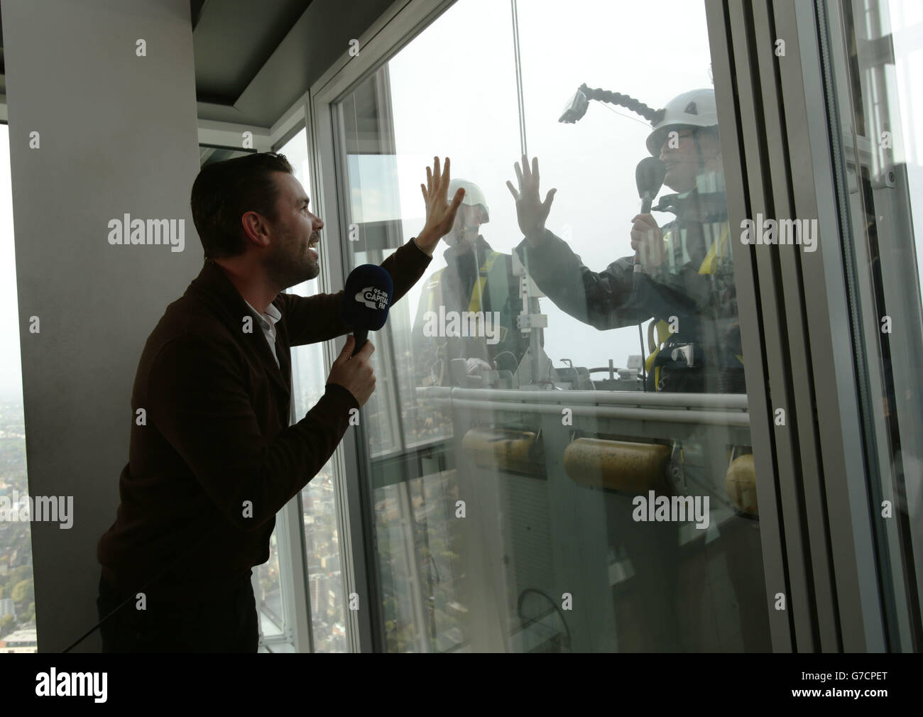 Capital Breakfast-Moderator Dave Berry spricht mit seiner Co-Moderatorin Lisa Snowdon, während sie die Fenster in der Galerie wäscht, nachdem sie während einer Live-Übertragung von The Shard in London eine Spendenaktion im Rahmen von Global Make Some Noise, dem größten Wohltätigkeitsanruf des Radios, verloren hatte. Stockfoto