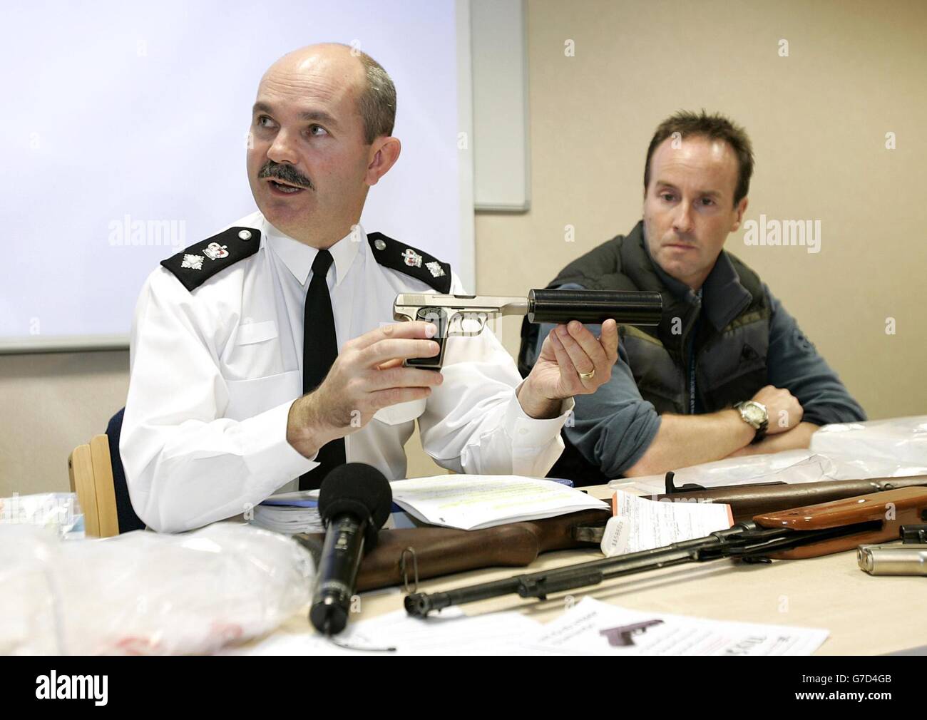 Hauptuntertr. Archie Torrance (links) und Det Chief Insp. Simon Cunneen (rechts) mit einer wiederhergestellten Browning-Pistole, ausgestattet mit einem Maschinengewehr-Schalldämpfer, während einer Pressekonferenz auf der Polizeistation Lewisham. Die Polizei nutzte den Millennium Dome als Basis, um gestern Abend einen massiven Schlag gegen die mit Waffen umstürzenden Yardie-Drogenhändler zu starten. Die Operation Vezere war drei Monate in der Planung und beinhaltete 400 Offiziere in stechsichere Westen. Es war der Höhepunkt eines Blitzes gegen Drogendepots mit Verbindungen zu jamaikanischen Gangstern, bei dem die Polizei in den letzten Wochen 15 Waffen beschlagnahmt hat. Siehe PA Geschichte POLIZEI Guns. PA Foto: Edmond Terakopian. Stockfoto