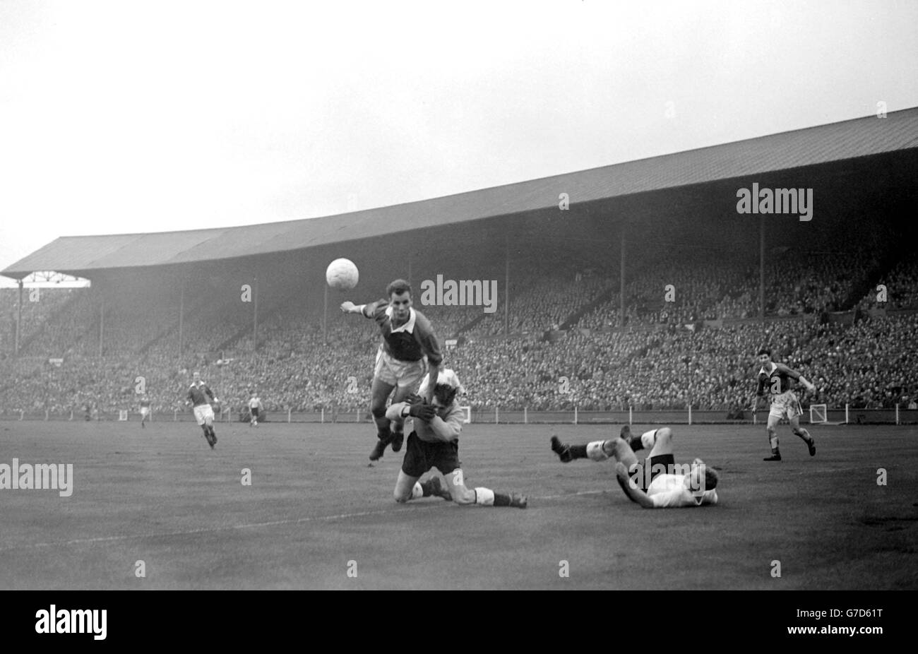 Englands Torhüter Ray Wood verdeckt sich unwillkürlich - und wer würde es nicht tun, wenn der Großteil des walisischen Mittelstürters John Charles während eines Angriffs auf das England-Tor beim internationalen Fußballspiel in Wembley, London, über ihn emporragte. 21/02/04: Der ehemalige Stürmer aus Leeds, Juventus und Wales ist im Alter von 72 Jahren gestorben. Stockfoto