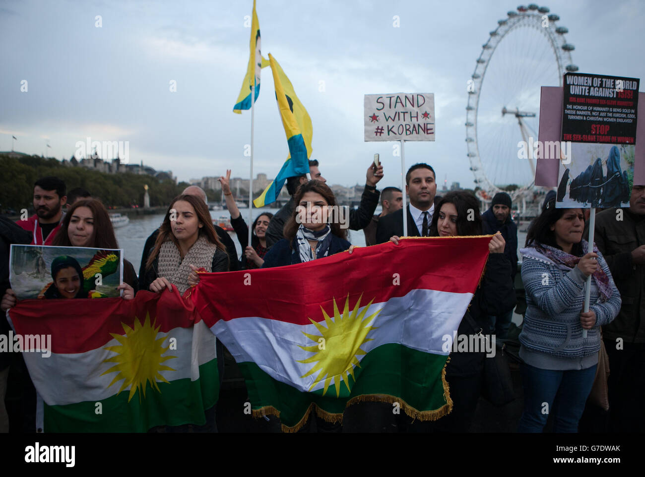 Menschen demonstrieren auf der Westminster Bridge im Zentrum von London mit kurdischen Fahnen und Transparenten gegen die Bedrohung der Kurden und anderer Minderheiten in Syrien und im Irak durch den IS. Stockfoto