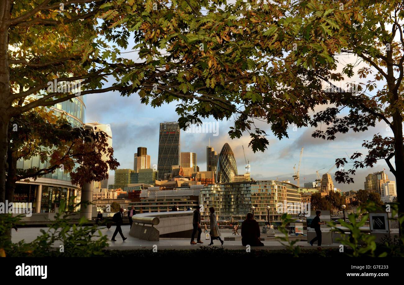 Die City of London ist im Hintergrund zu sehen, wenn Pendler die Herbstfarben, London, passieren. Stockfoto