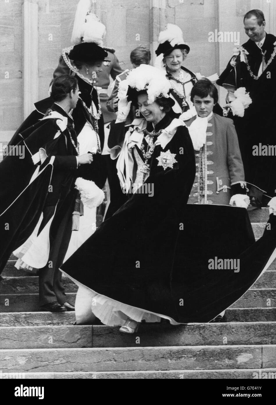 Die Königin lacht, als sie sich an ihrem Hut festhält, als sie den jährlichen Gottesdienst des Edlen Orden des Gewanters im Schloss Windsor verlässt. Mit ihr auf den Stufen der Freien Kapelle St. Georg sind (l-r) der Prinz von Wales, die Königin von Dänemark, die Königin Mutter und der Großherzog von Luxemburg. Stockfoto